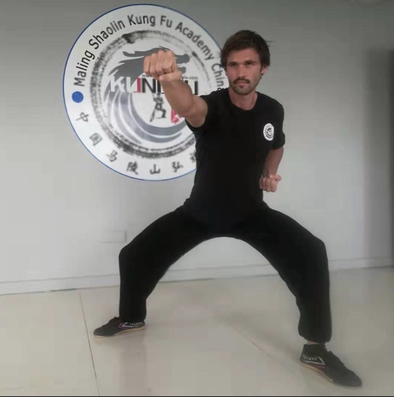 Codie holding a horse stance in black training kit at a Shaolin kung fu academy