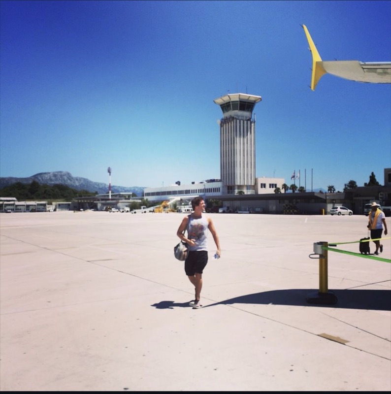 Codie walking across the tarmac to a plane in Croatia, bag over his shoulder