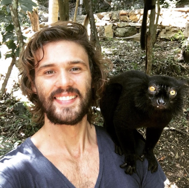 Codie in the forest during reef and wildlife conservation work, a black lemur perched on his shoulder